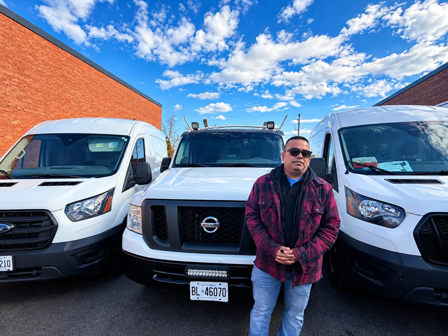 A Just Air team member standing in front of the company's service vans outside the shop